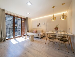 Una sala de estar moderna con sofá, mesa de comedor, sillas y un balcón con vistas.