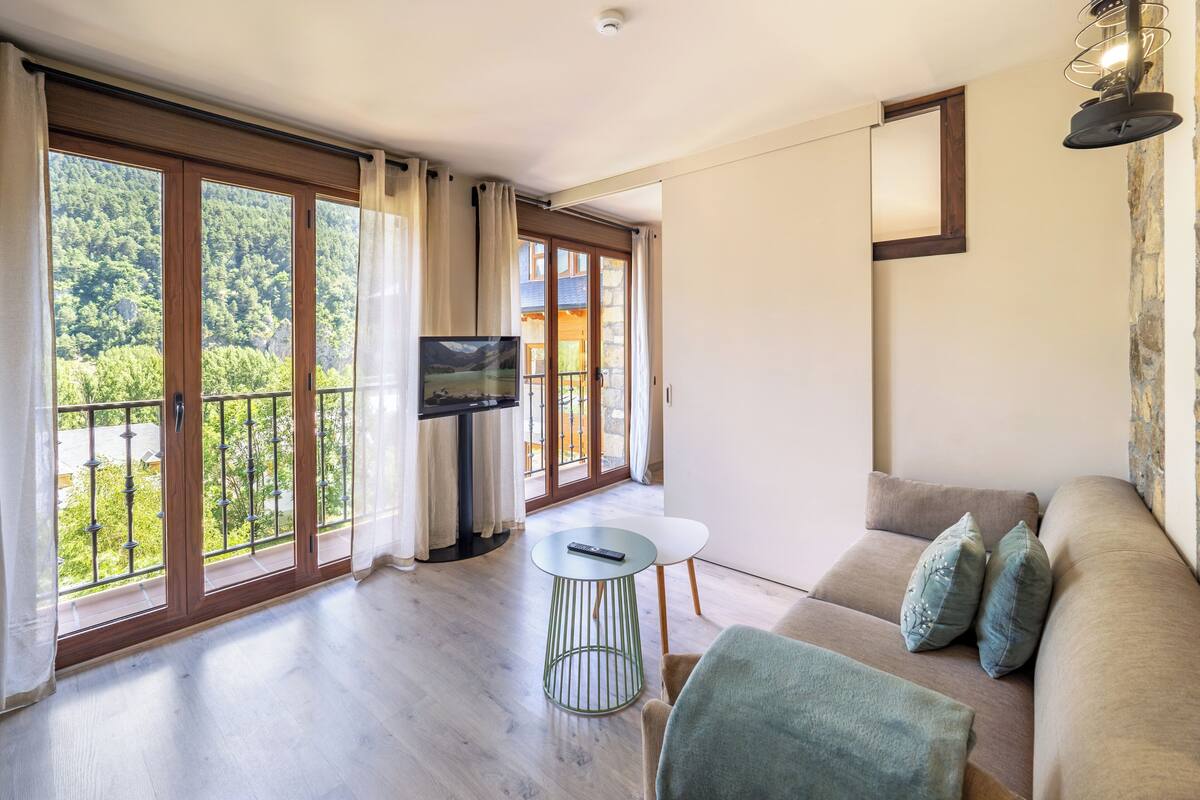 A spacious living area with a sofa, a small table, and a TV on a stand.