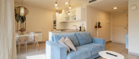 Una sala de estar moderna con un sofá, una mesa de comedor con sillas, una zona de cocina y una puerta.