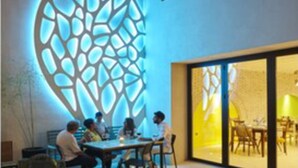 Un comedor interior con una moderna instalación de luces geométricas en la pared.