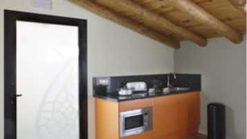 Una cocina con vigas de madera, una puerta de marco negro y una pequeña encimera con electrodomésticos.