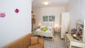 A bedroom with a bed, bedside tables, a dresser, and a mirror. - Pension Ageliki (Sifnos)