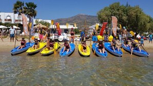 A beach with several small boats lined up on the shore, people in the water, and a mountainous backdrop. - Pension Ageliki (Sifnos)