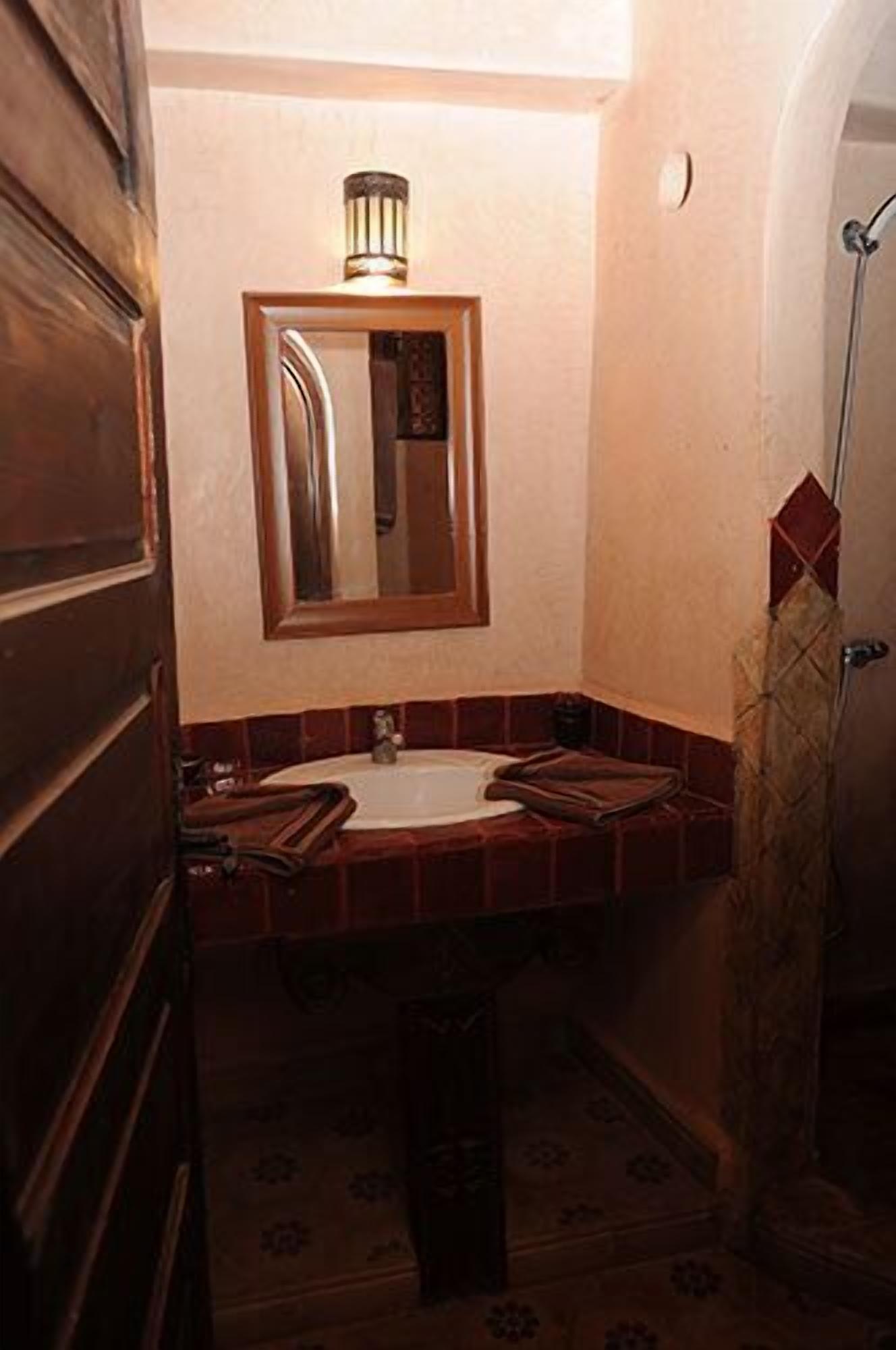 A bathroom with a wooden door, a sink with a mirror above it, and a shower curtain.