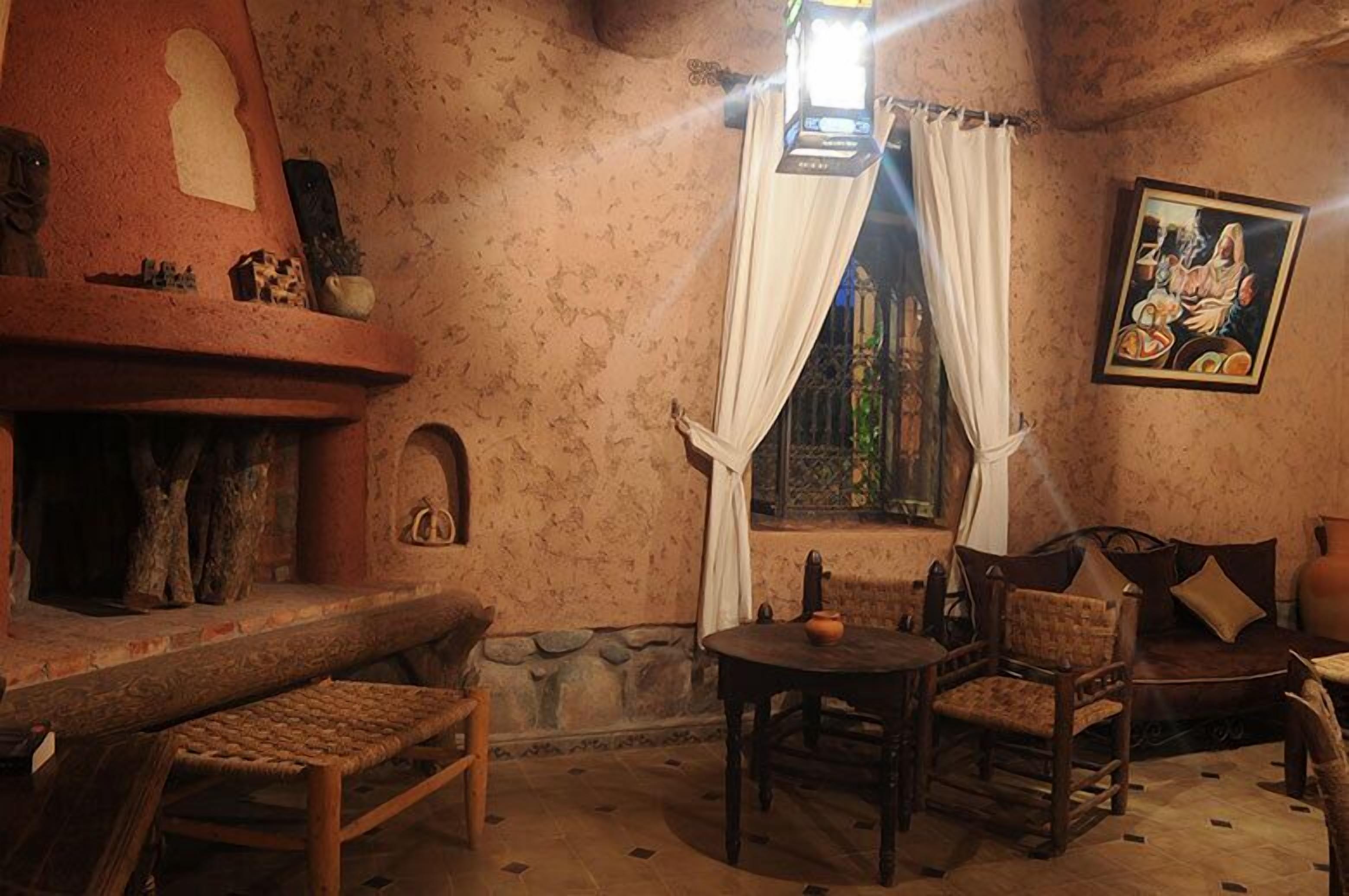 Una habitación acogedora con chimenea, pared de piedra, banca de madera, mesa con sillas y un cuadro en la pared.