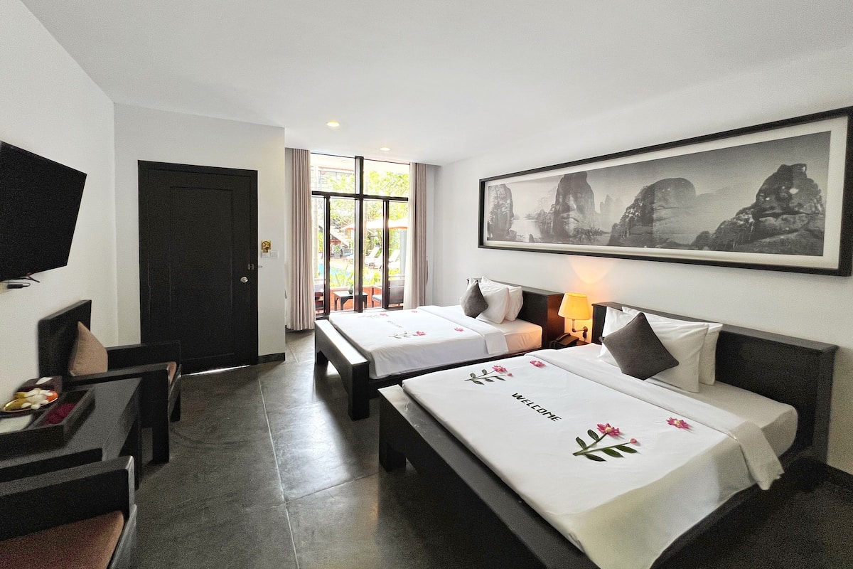 A hotel room with two beds, a television, and a large framed picture on the wall.