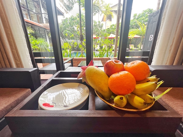 Un frutero con manzanas, naranjas y plátanos sobre una bandeja.