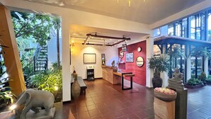 A spacious lobby with a reception desk, a map on the wall, and a large window overlooking a garden. - The Bliss Angkor (Siem Reap)
