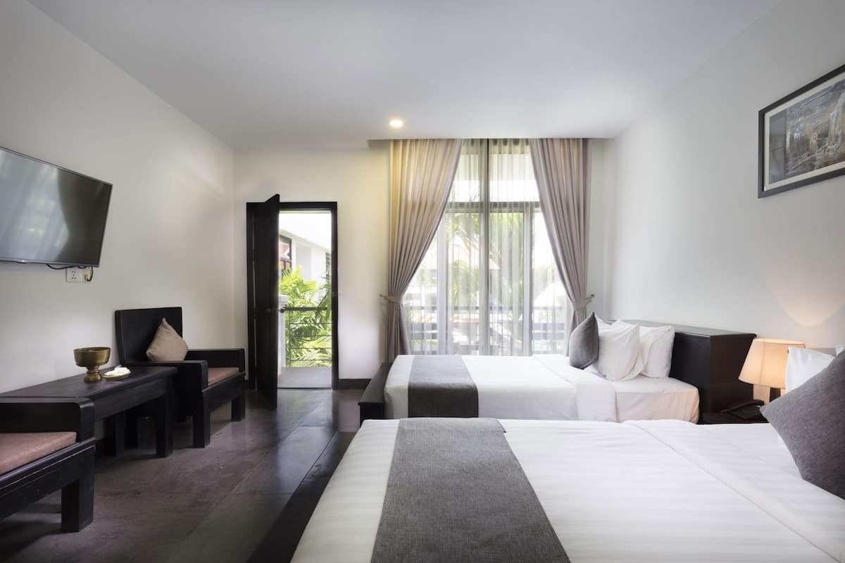 A hotel room with a bed, a desk, a chair, a television, and a window with curtains.