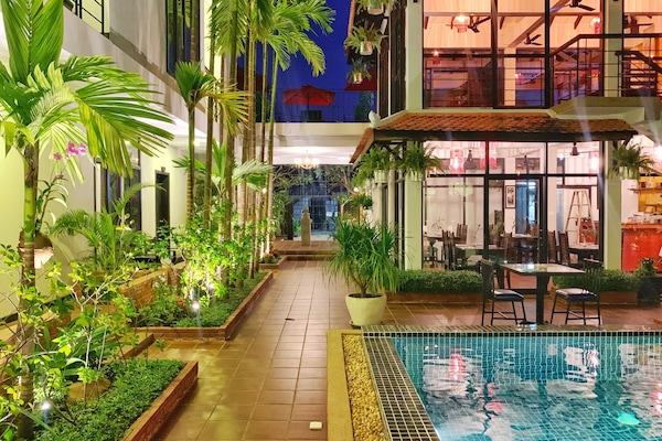 Una piscina al aire libre, sombrillas, sillones reclinables de piscina