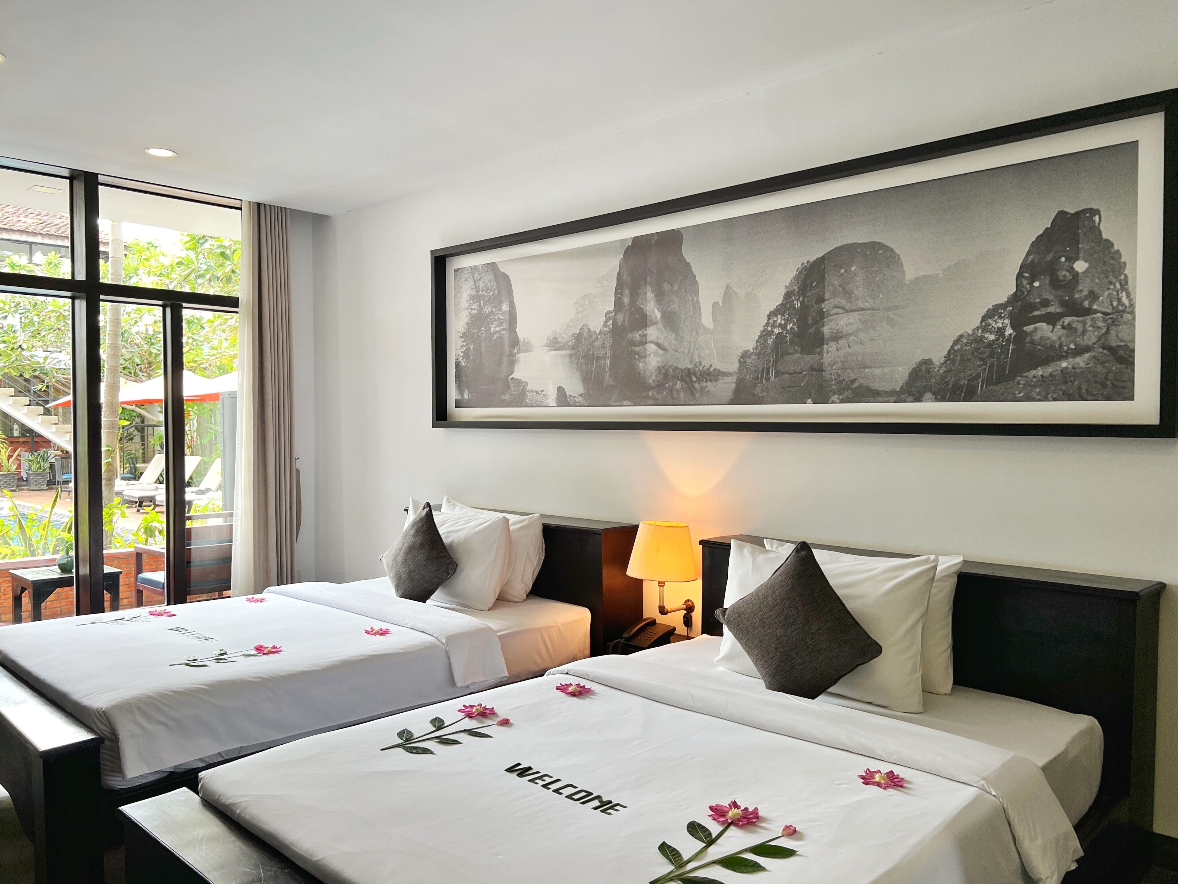 Een hotelkamer met twee bedden, een groot gepresenteerd beeld van rotsformaties en uitzicht op het buitengebied door grote ramen.
