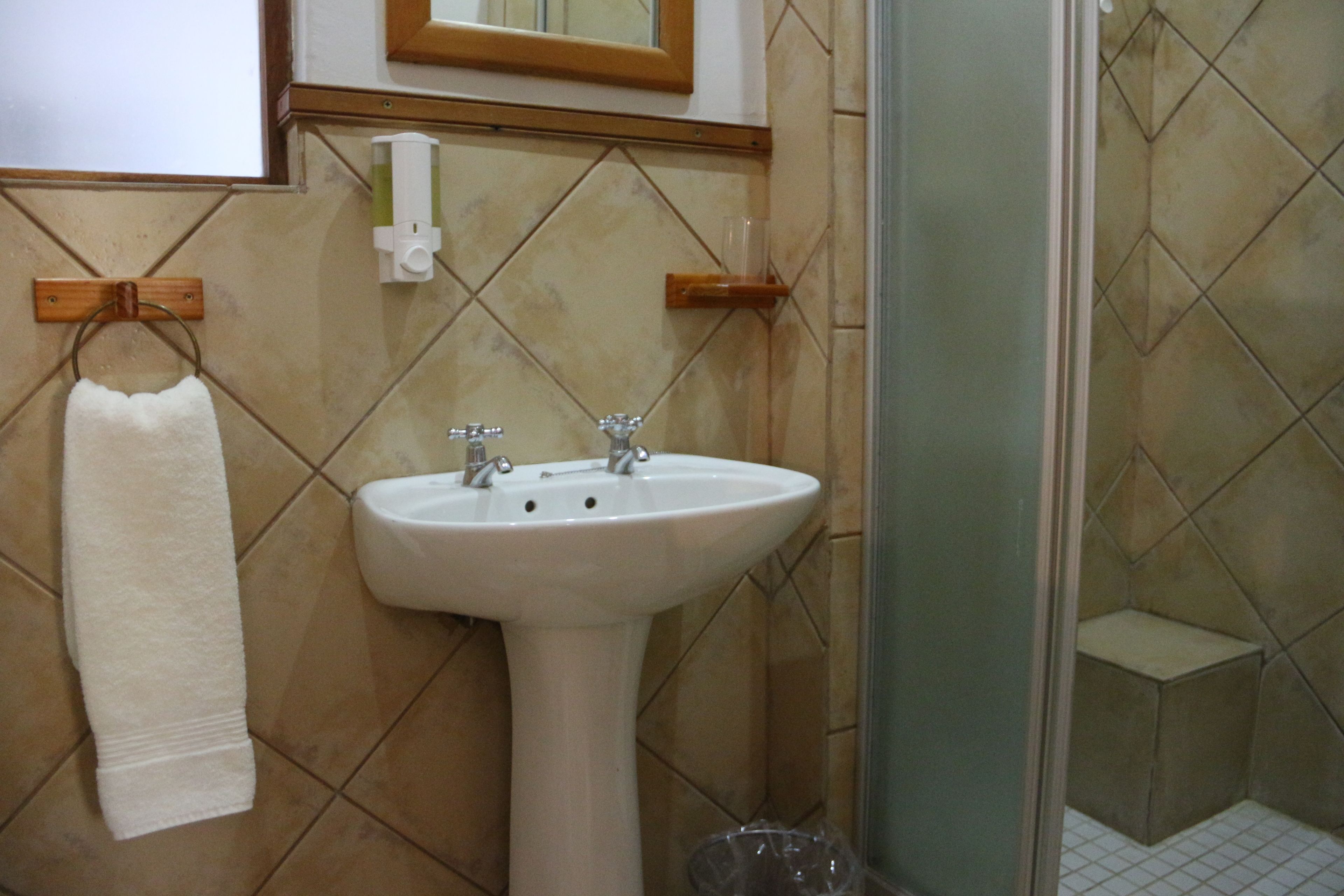 A bathroom with a white sink, a towel rack, and a glass shower enclosure.