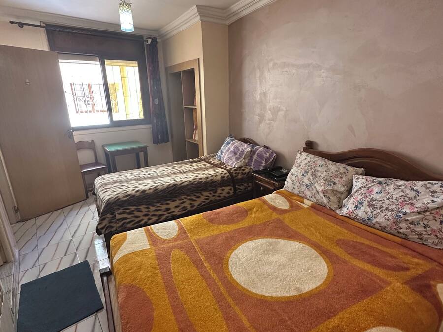 A bedroom with a bed, a chair, a desk, and a wardrobe.