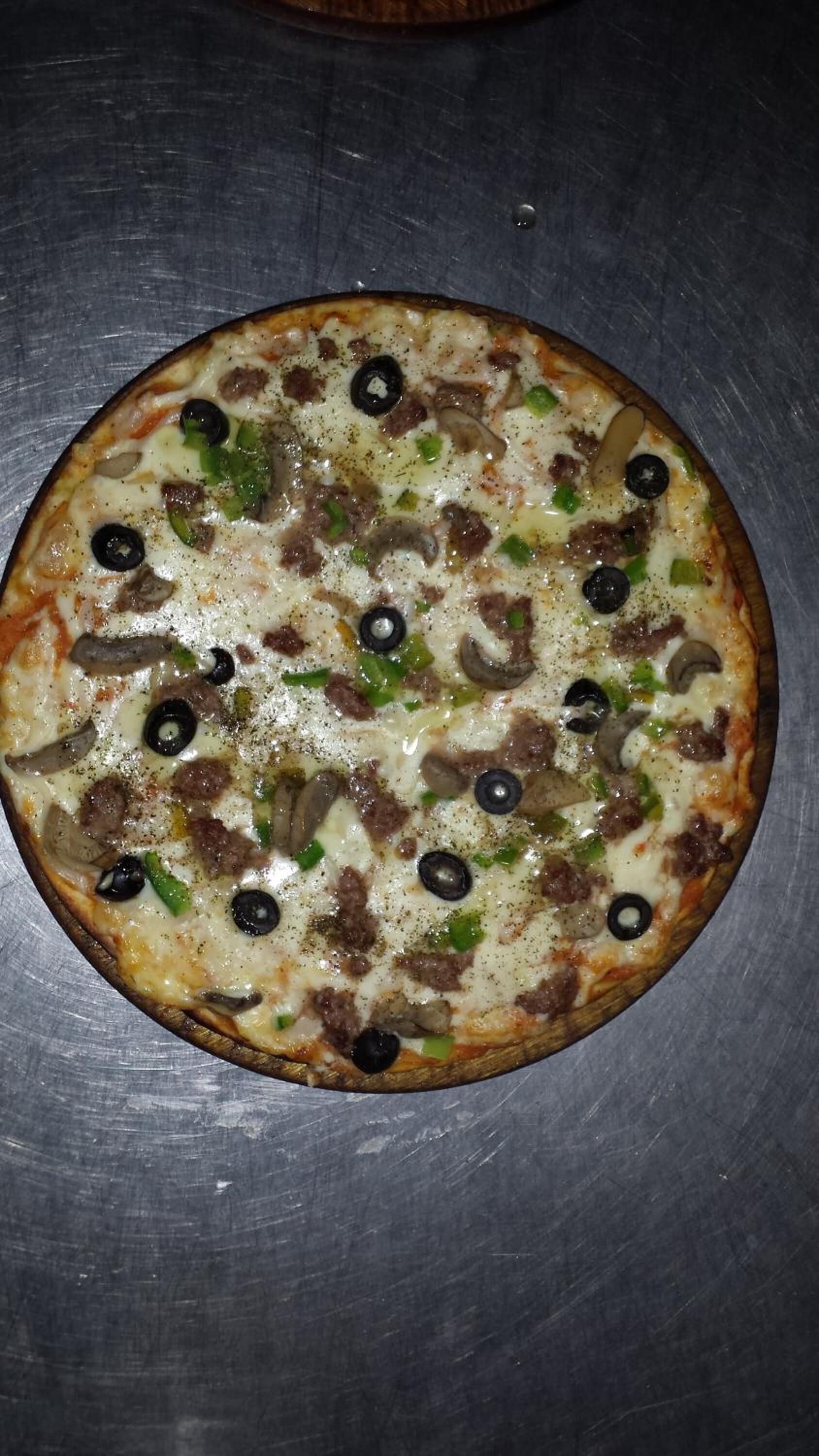 Una pizza con diferentes ingredientes sobre una superficie metálica.