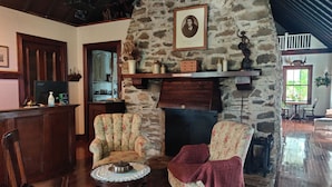 Una sala de estar acogedora con chimenea de piedra, sillones con estampado floral, una mesa de centro de madera y una estantería.