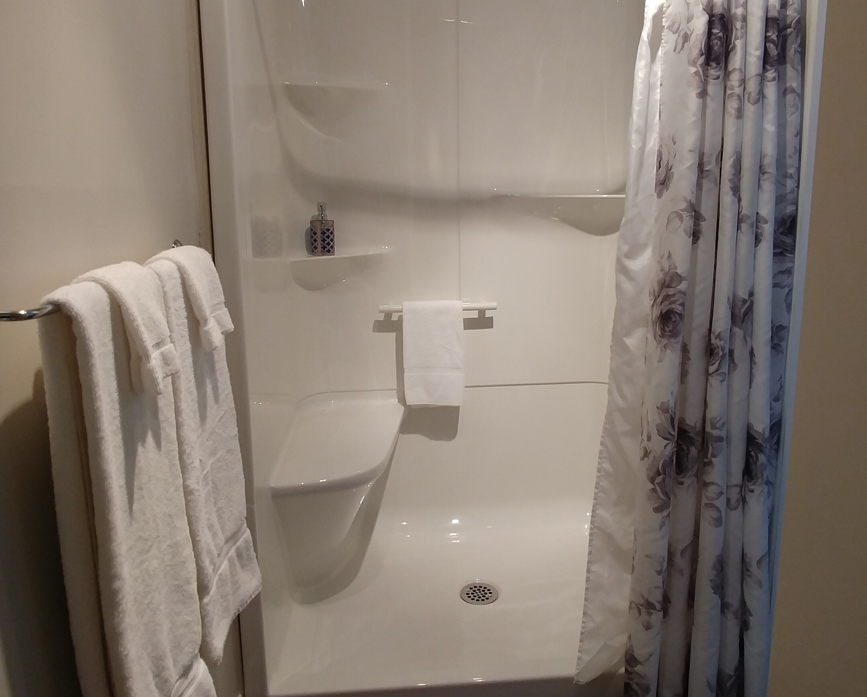 A bathroom with a toilet, a towel rack, and a shower curtain.