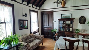 Una habitación acogedora con un sofá estampado, una mesa de comedor con sillas, una estantería de madera y una araña.