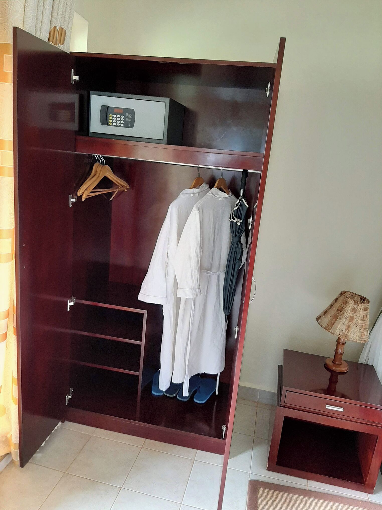 A wardrobe with a built-in safe, a hanging rack, and a small table with a lamp.