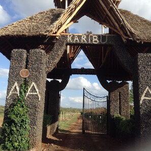 A rustic gate with 'WELCOME' inscribed, leading to a path. - AA Lodge Amboseli (Amboseli)