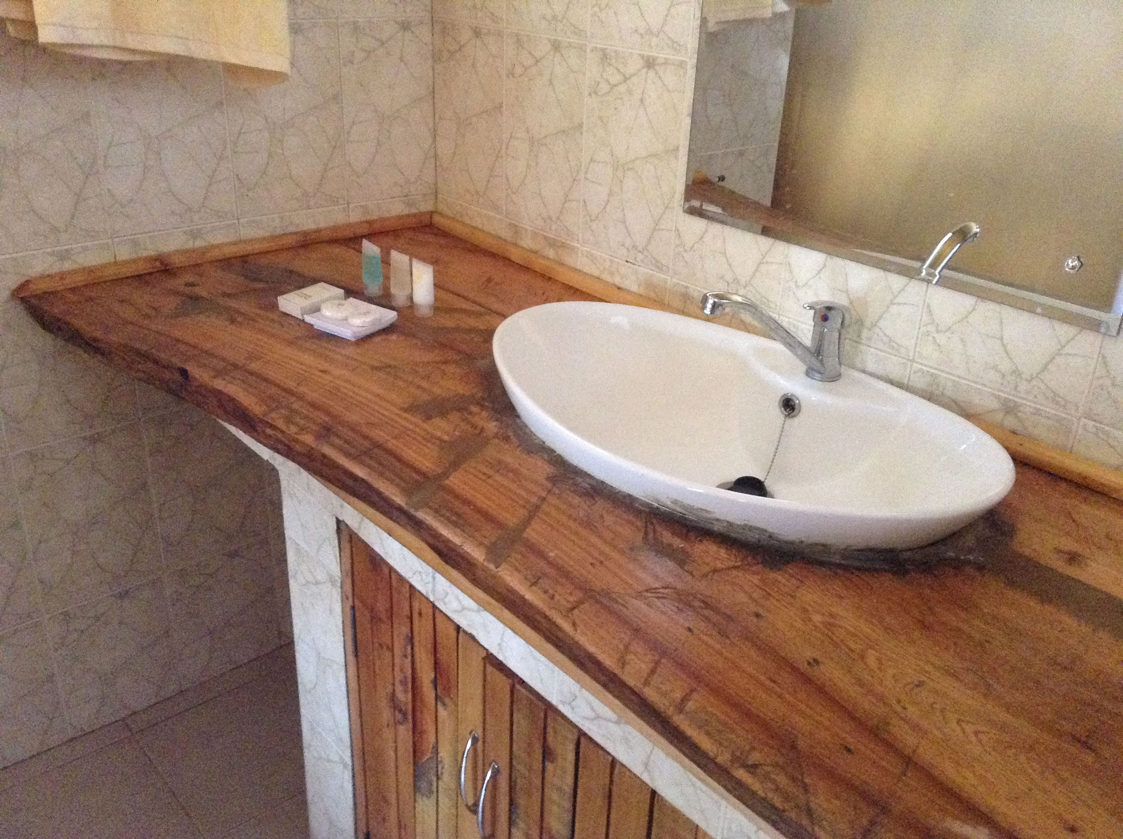 A bathroom with a wooden vanity, a white sink, and a mirror above it.