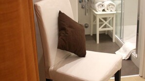 A bathroom with a white chair, a glass shower enclosure, a sink, and a mirror. - St. Peter's Relax (Rome)