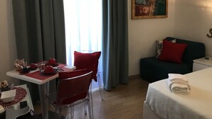 A hotel room with a dining table, red chair, and a bed with a white cover. - St. Peter's Relax (Rome)