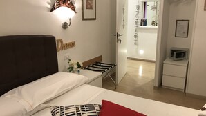A hotel room with a bed, a bedside table, a wall-mounted lamp, a framed picture, a mirror, a wardrobe, and a microwave. - St. Peter's Relax (Rome)