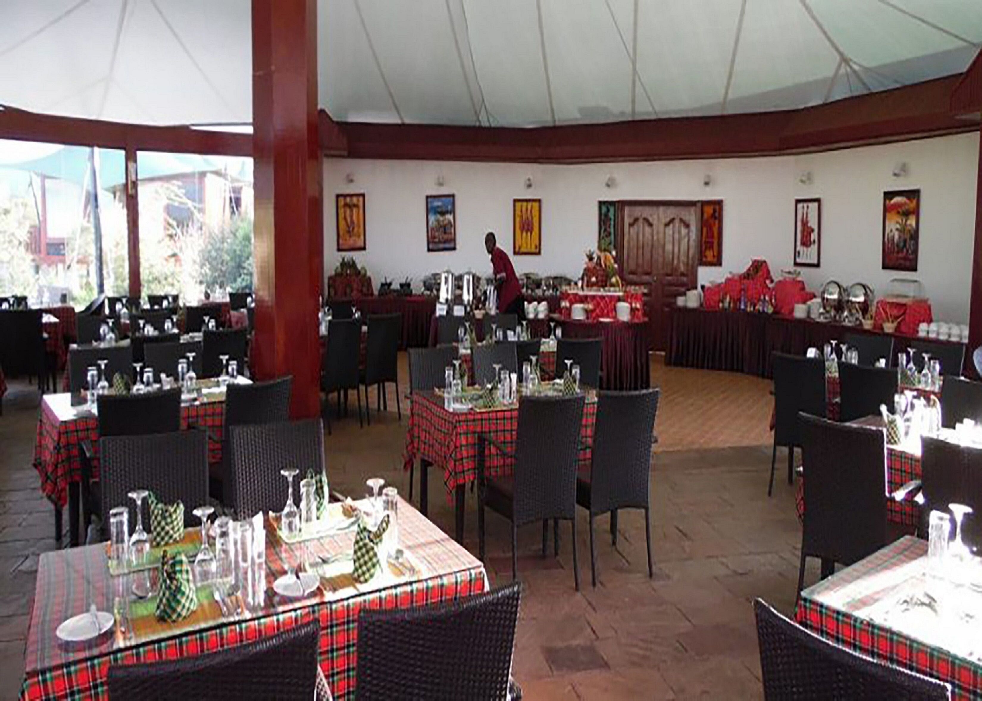 A restaurant with multiple tables set for dining, featuring red and black checkered tablecloths.