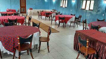 A dining area with tables covered in red and white checkered tablecloths, wooden chairs, and blue walls.