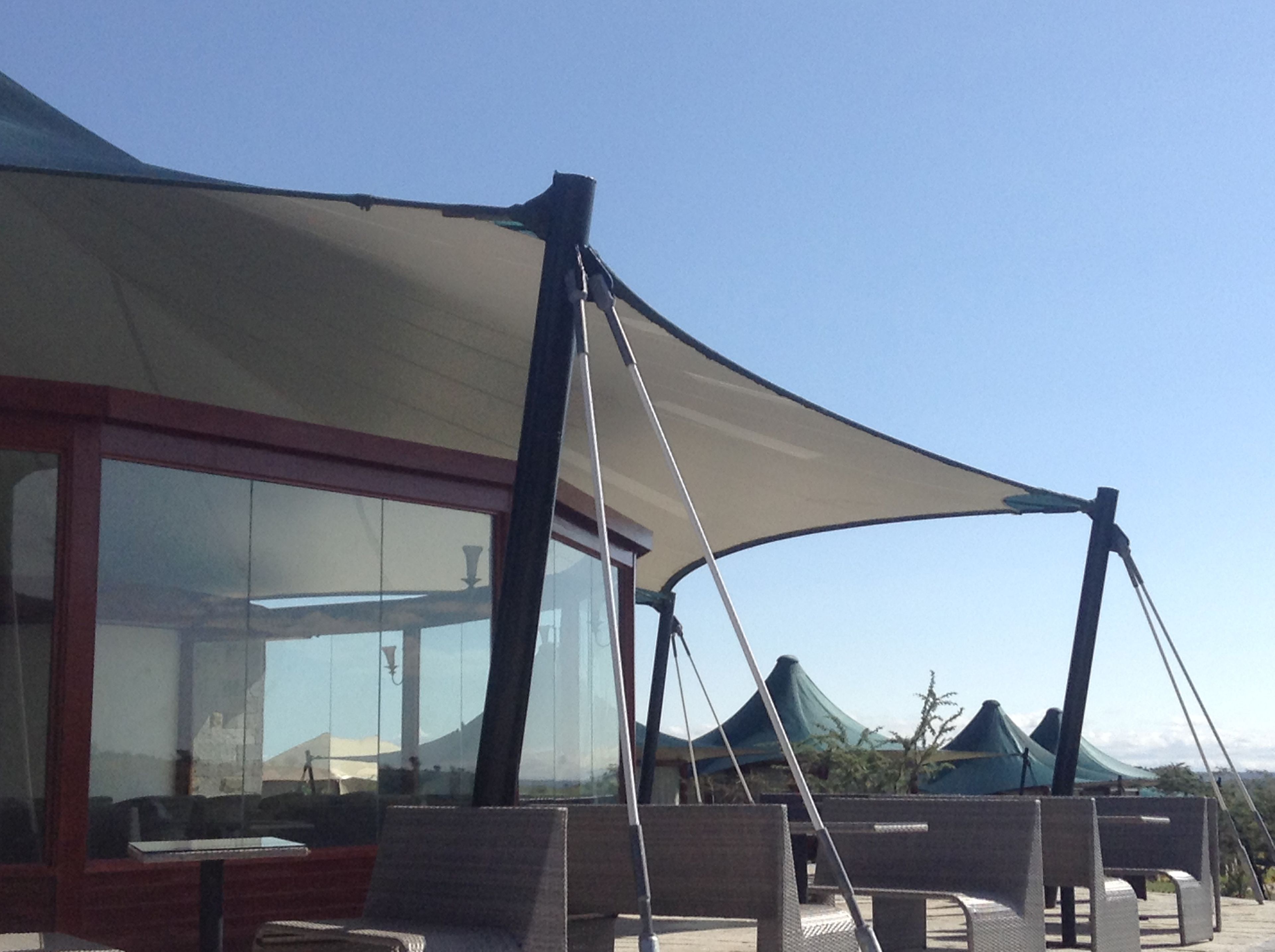 Un área de estar al aire libre, cubierta con cerramiento de vidrio y un dosel grande.