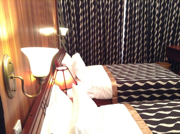 Una habitación de hotel con una cama, una mesita de noche, una lámpara y una cortina estampada.