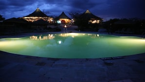 Un espace piscine aménagé pour la nuit, offrant une vue dégagée sur le bord du bassin et un panneau indiquant la profondeur de l’eau.