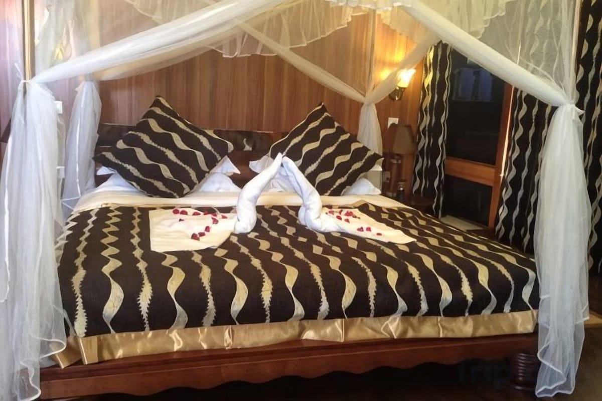 Una cama con dosel, dos almohadas y una decoración de toallas.