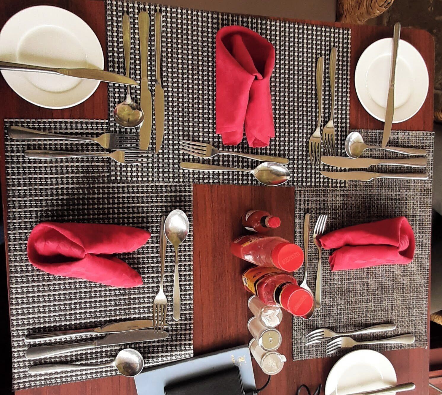 A dining table set with multiple place settings, including plates, cutlery, and napkins.