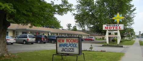 Een Holiday Motel bord met een sterrensymbool en een reclamebord dat nieuwe kamers met whirlpools en jacuzzi's aanprijst.