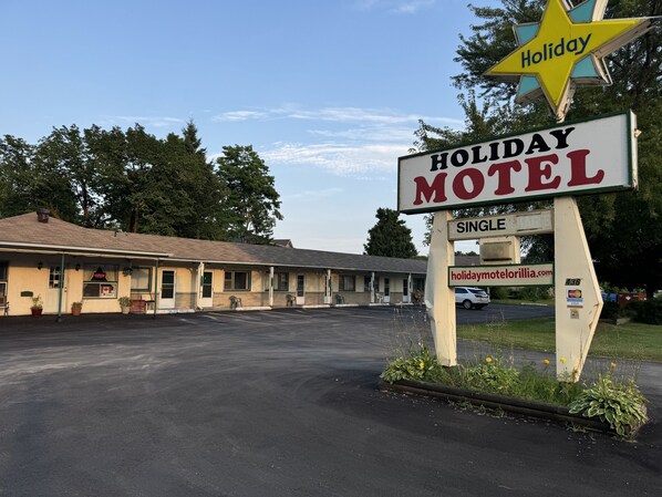 A Holiday Motel with a single-story building, a parking lot, and a sign indicating it's a Holiday Motel.