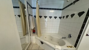 Un baño con bañera, zona de ducha y espejo.