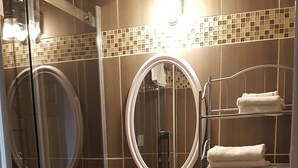 A bathroom with a glass shower enclosure, a sink with a mirror, and a toilet.
