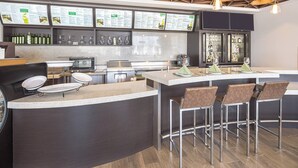 A modern bar area with a curved counter, bar stools, and a menu display.