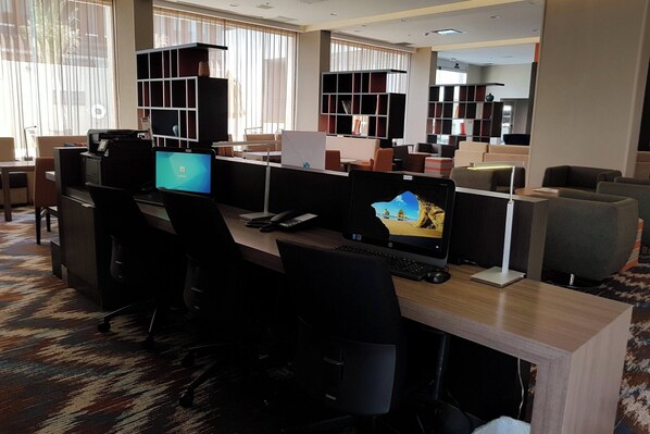 A modern office space with multiple workstations, ergonomic chairs, and built-in shelving.