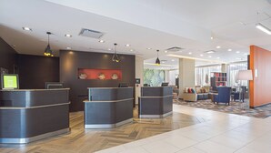 A modern reception area with a reception desk, a digital display, and a seating area with a patterned rug.