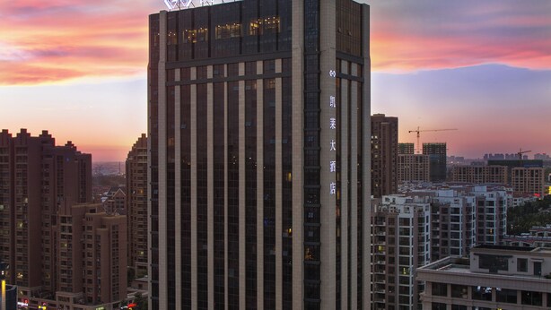 Un edificio alto con una entrada destacada y señalización.