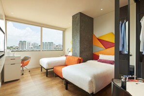 Een moderne hotelkamer met twee bedden, een bureau, een stoel en een groot raam met uitzicht op de stad.