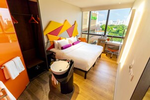 Habitación de hotel moderna con cama, escritorio, baño con lavamanos y vista a la ciudad.