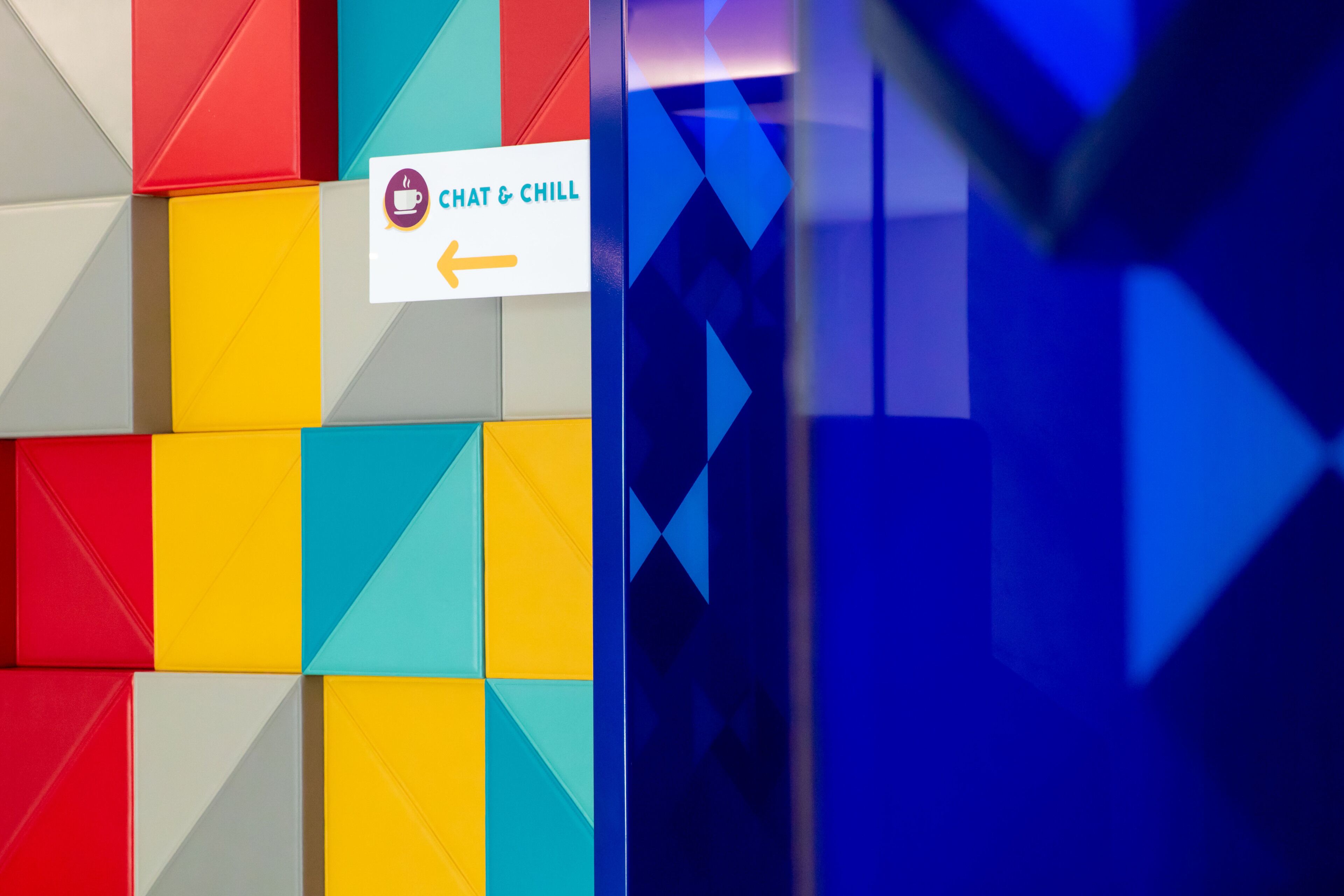 Un motif géométrique coloré orne le mur, et un panneau indique un espace dédié à la discussion et à la détente.
