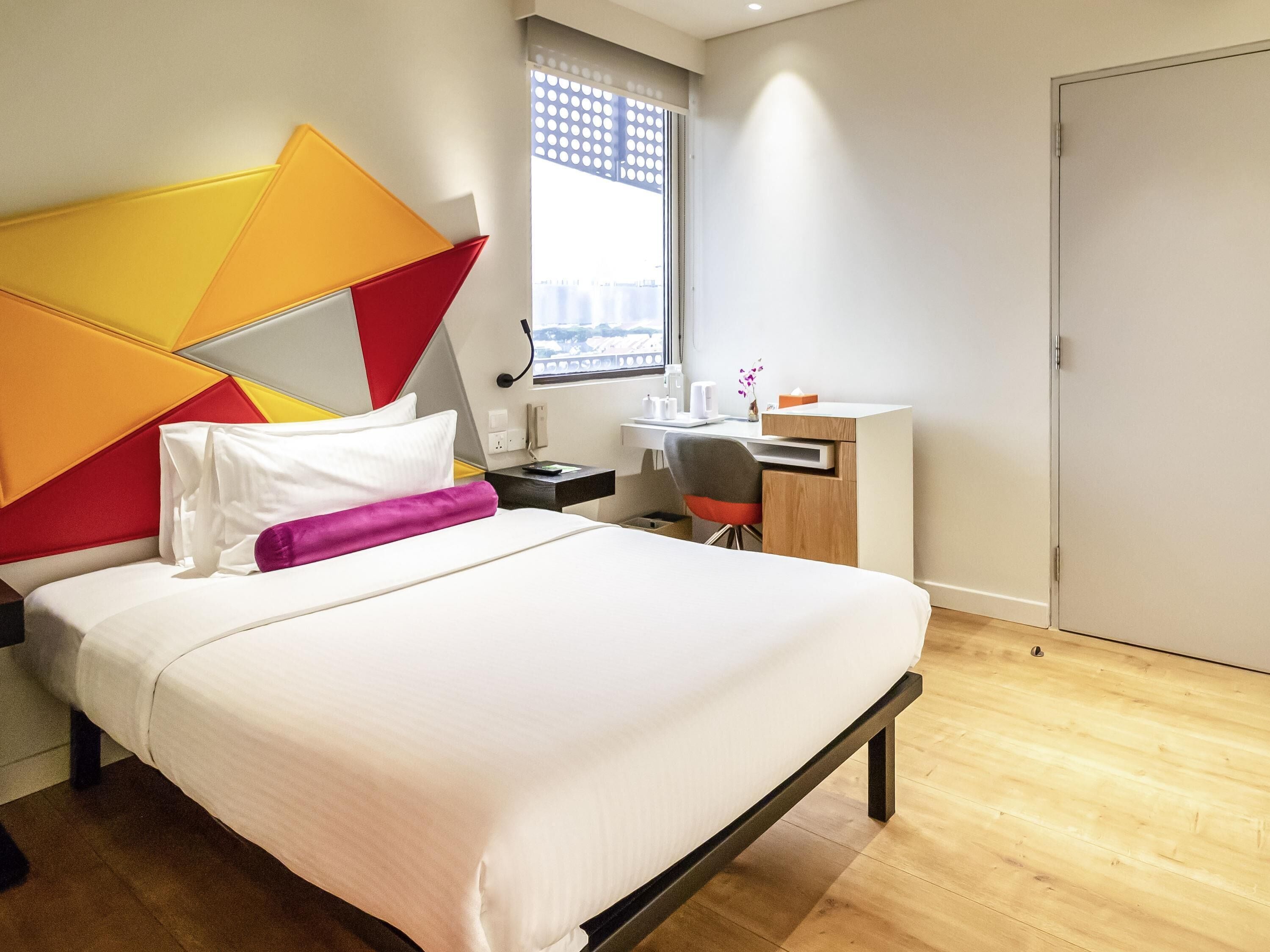 Ein modernes Hotelzimmer mit Bett, Schreibtisch und Fenster mit Blick auf die Stadt.