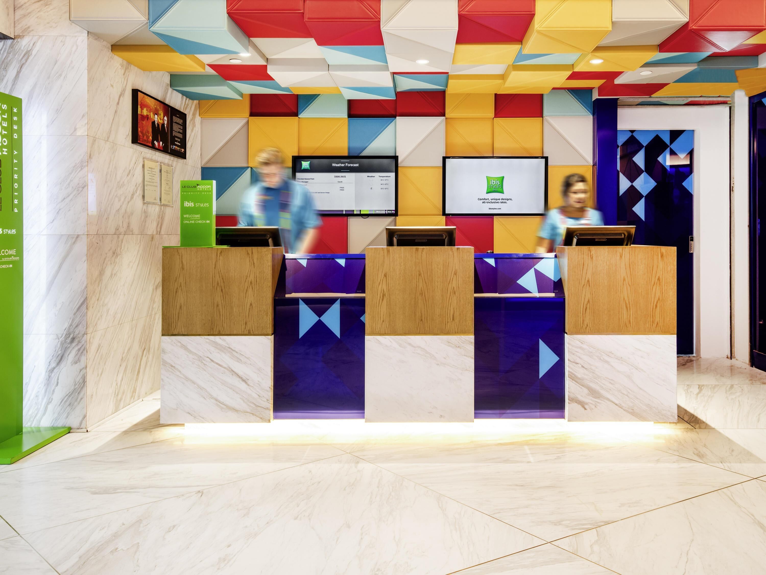 A hotel reception desk with a digital screen displaying the weather forecast.