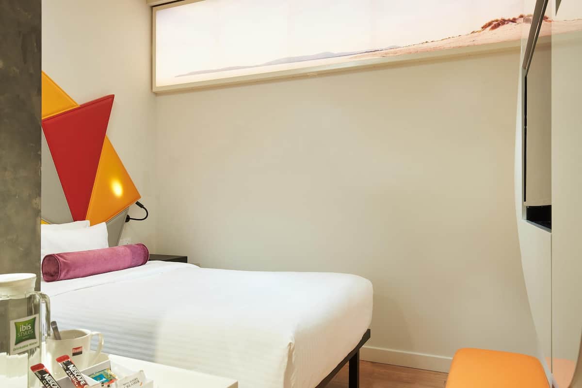 Een hotelkamer met een bed, nachtkastje en een raam met uitzicht.