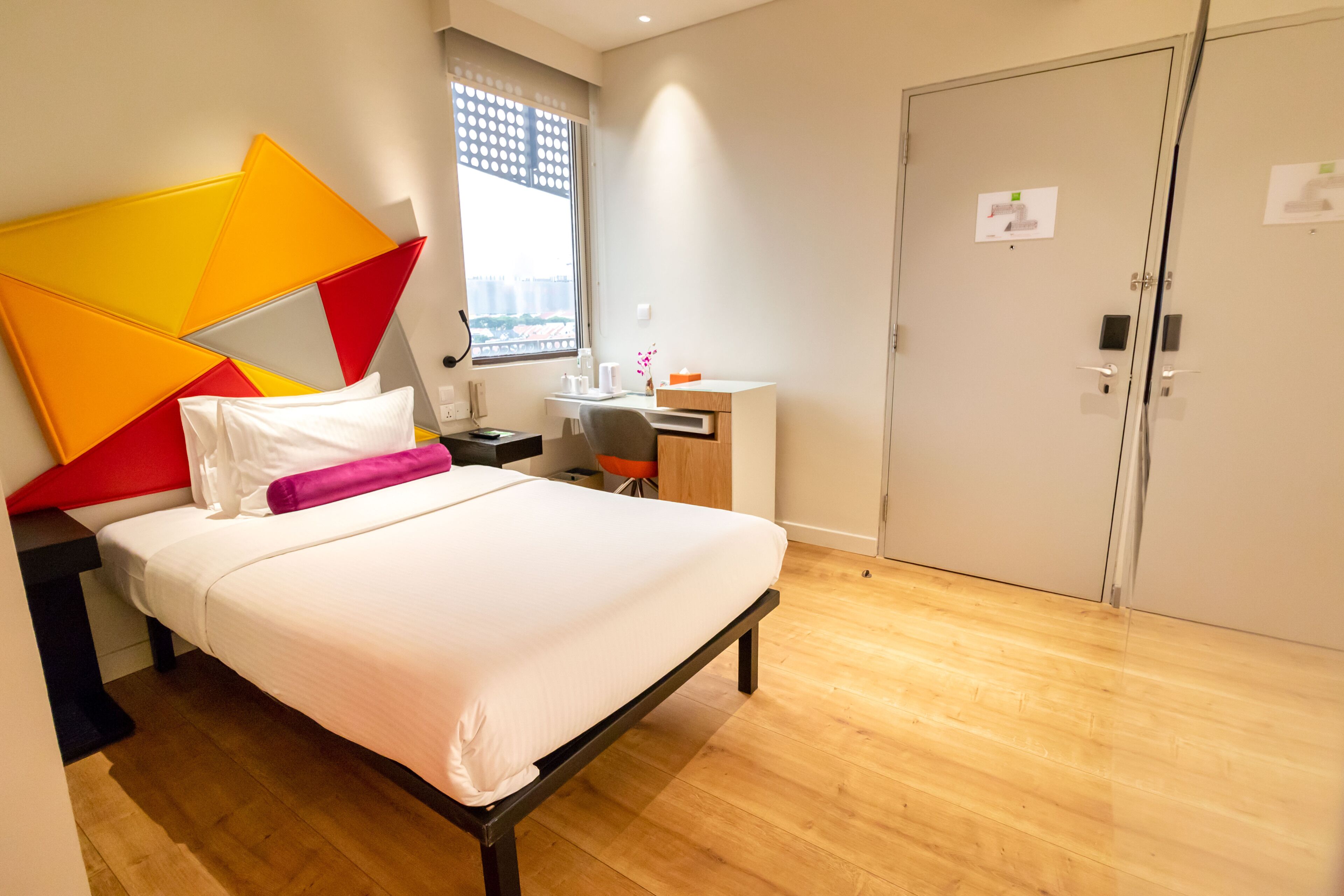 Una habitación de hotel moderna con una cama grande, un escritorio y un armario.