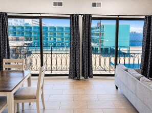 Quarto de hotel moderno com varanda, mesa de jantar e sofá.